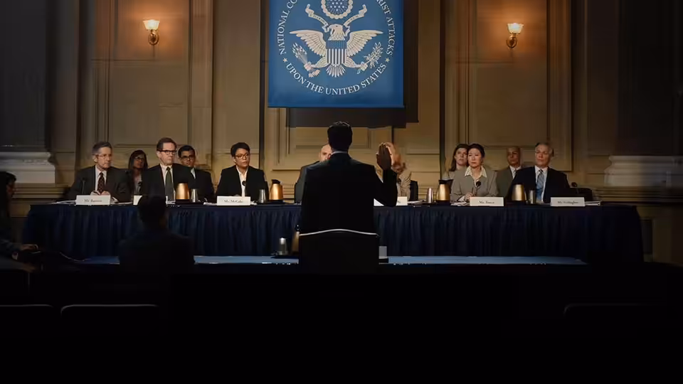 Officials sit at a long table during a formal government hearing