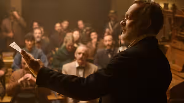 Captain Jefferson Kyle Kidd reads a sheet of news aloud to a seated audience
