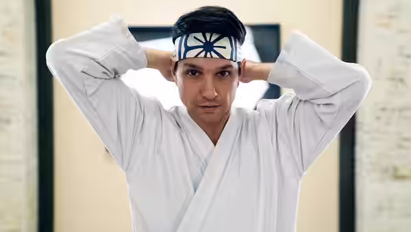 Daniel LaRusso (Ralph Macchio) ties his headband over a white karate gi