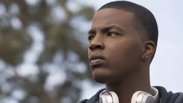 Spencer James (Daniel Ezra) looks to the side with headphones around his neck