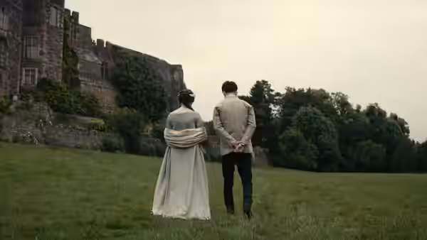 Hal (Timothée Chalamet) and a woman stand facing the grounds of a stone castle
