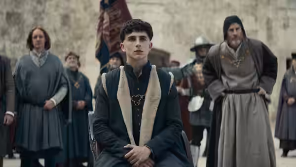 Hal (Timothée Chalamet) stands among clerics and attendants in a pale stone hall