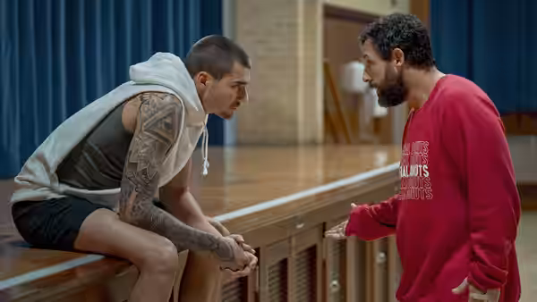 Bo Cruz (Juancho Hernangómez) sits on a gym railing as Stanley Sugerman (Adam Sandler) talks to him