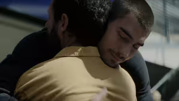 Two men embrace closely inside a building