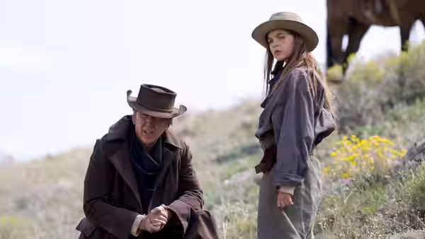 Colton Briggs (Nicolas Cage) crouches beside Brooke Briggs (Ryan Kiera Armstrong) in a field