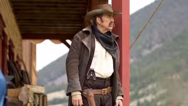 Colton Briggs (Nicolas Cage) stands in a doorway wearing a long coat and cowboy hat