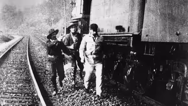 Bandits confront railway workers beside a locomotive on the tracks