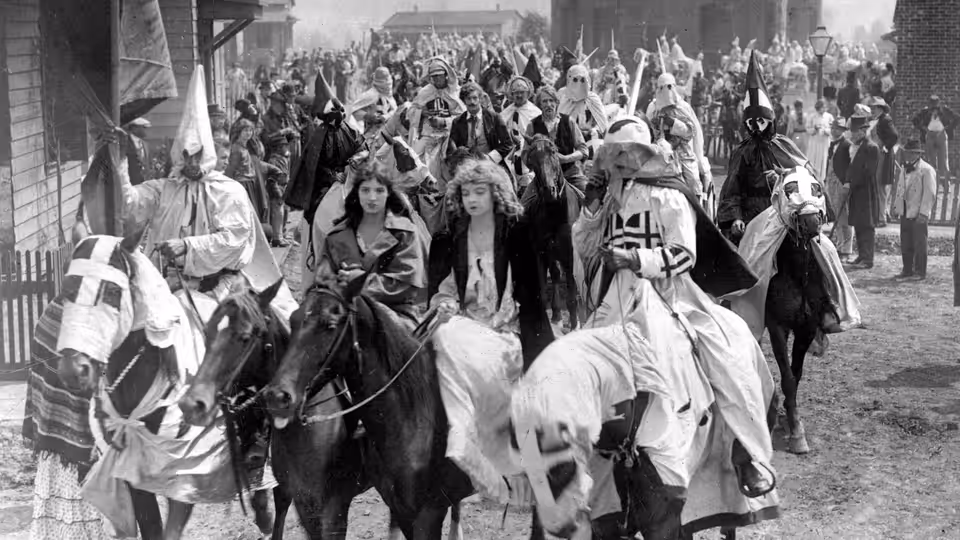Elsie Stoneman and Margaret Cameron ride through town amid a Ku Klux Klan procession