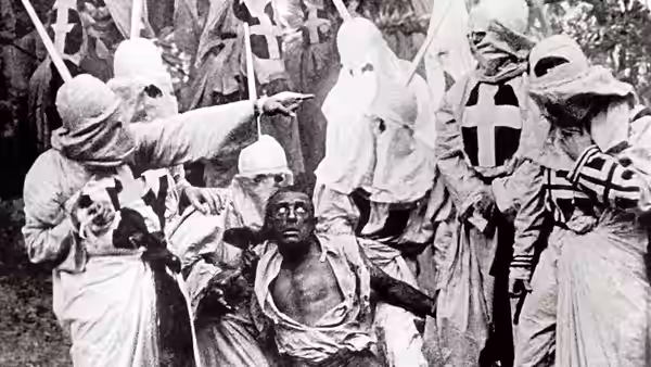 Ku Klux Klan members surround Gus, pointing toward him as he sits on the ground