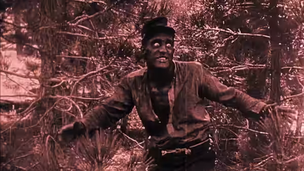 Gus stands among bare tree branches with his arms outstretched