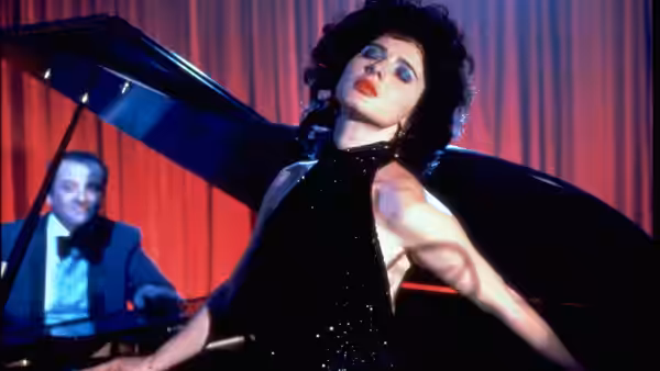 Dorothy Vallens (Isabella Rossellini) leaning against a grand piano on stage