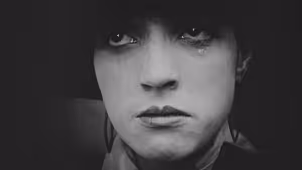 A tearful young woman looks ahead in close-up