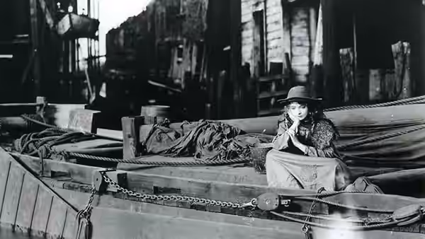 Lucy Burrows (Lillian Gish) sits among bundled laundry in a cart on a city street