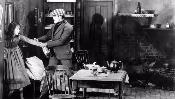 Battling Burrows (Donald Crisp) grips Lucy Burrows (Lillian Gish) by the arm in a kitchen