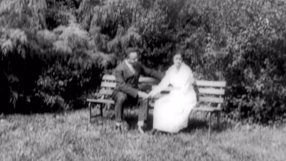A man and woman sit together on a park bench