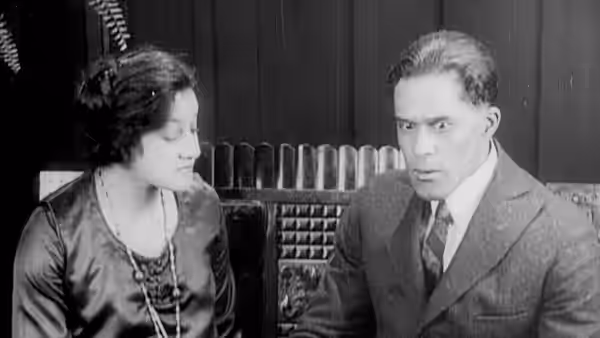 A woman and a suited man sit beside a telephone switchboard