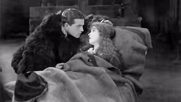 David Bartlett (Richard Barthelmess) leans over Anna Moore (Lillian Gish) beneath blankets