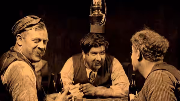 Three men sit around a table beneath a hanging lantern