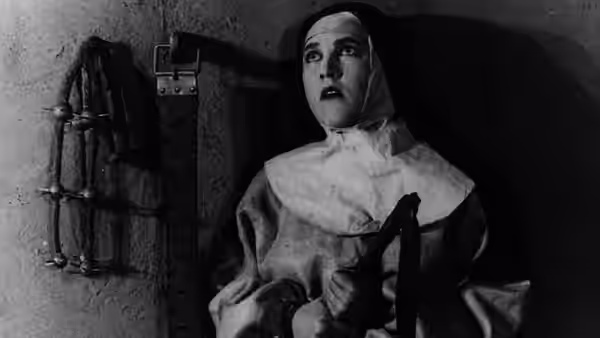 A woman in a head covering clutches a dark object against her chest