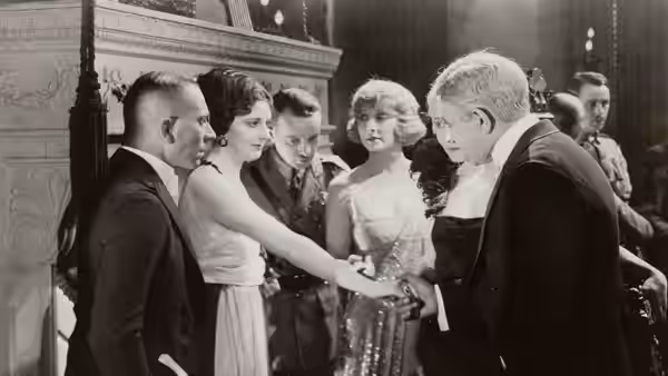 A group of formally dressed guests gather around women at a reception