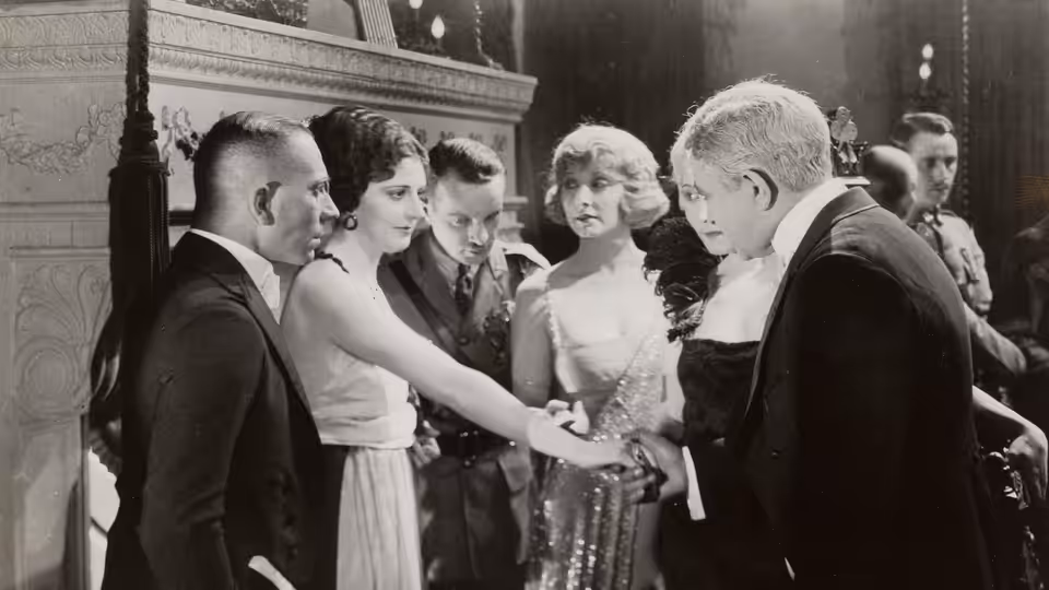 A group of formally dressed guests gather around women at a reception
