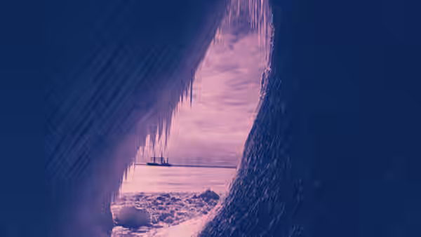 A sailing ship sits on the frozen sea, seen through a dark ice opening