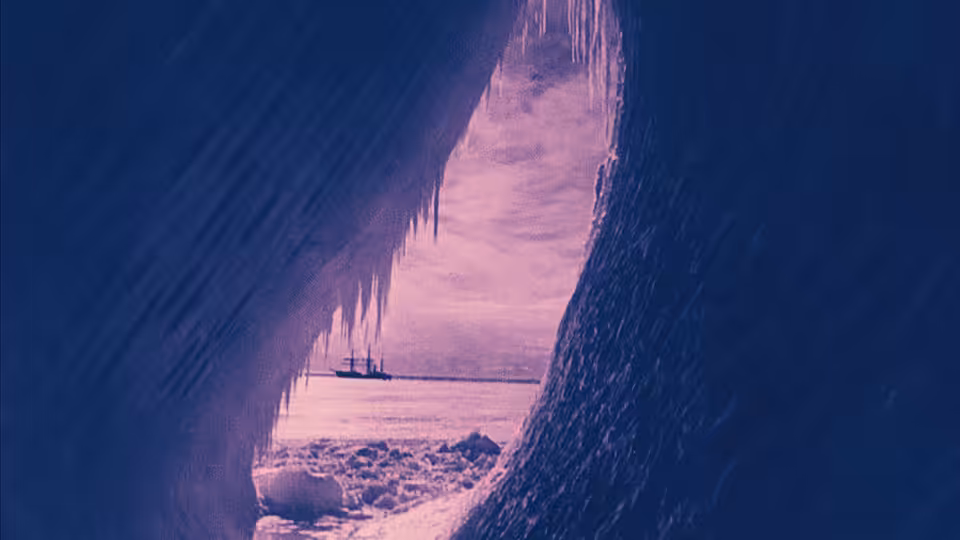 A sailing ship sits on the frozen sea, seen through a dark ice opening