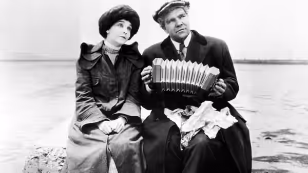 Trina (Zasu Pitts) and John McTeague (Gibson Gowland) sit by the sea as he plays an accordion