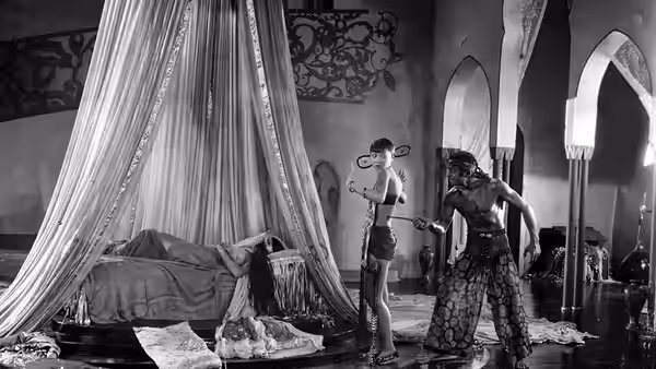 A turbaned man stands beside a curtained bed where a woman reclines