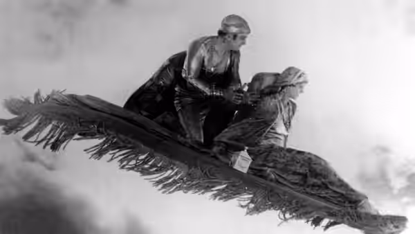 The Thief of Bagdad and the Princess ride a flying carpet above the clouds