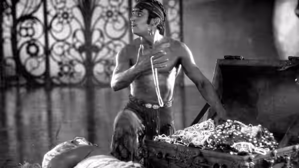 The Thief of Bagdad reaches into a chest overflowing with jewels