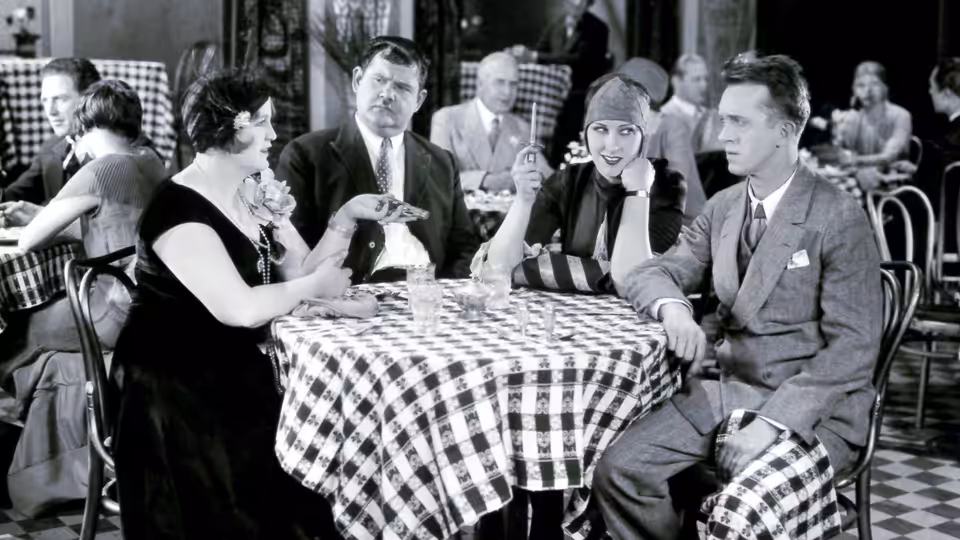 Jimmie Shannon (Buster Keaton) sits at a restaurant table with several companions