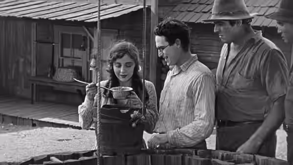 Mary Powers (Jobyna Ralston) samples food from a pot as Harold Hickory (Harold Lloyd) watches