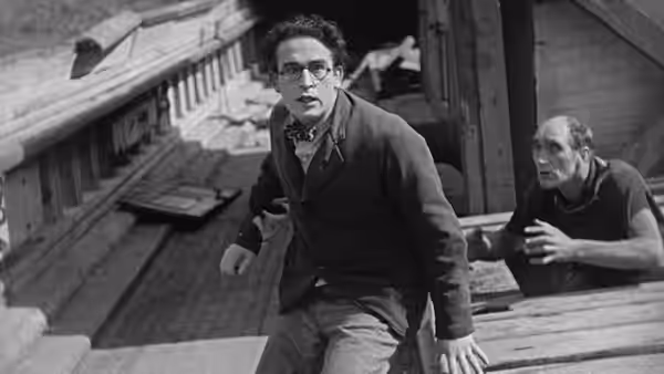 Harold Hickory (Harold Lloyd) climbs onto a porch as a man reaches after him