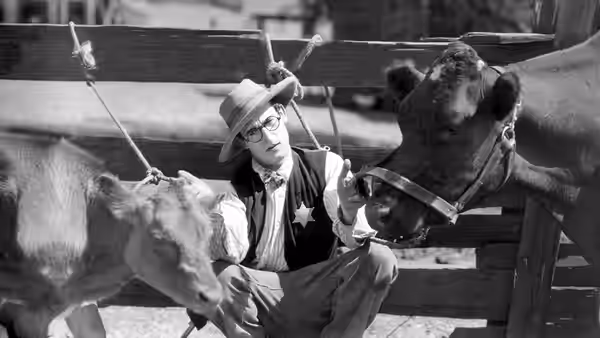 Harold Hickory (Harold Lloyd) crouches beside a cow in a barn
