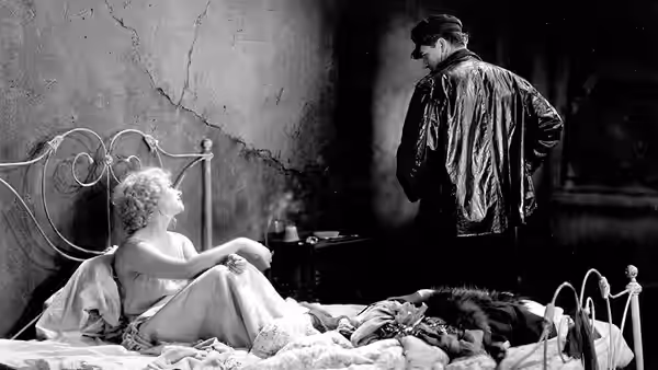 Lou (Olga Baclanova) sits on a bed as a man in a cap stands nearby