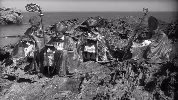 Robed religious figures stand among rocks on a shoreline