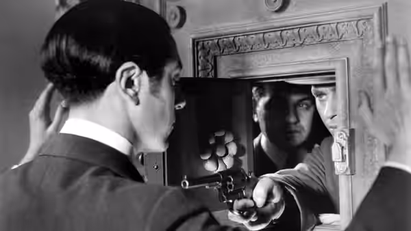A man faces a mirror while aiming a pistol at his reflection