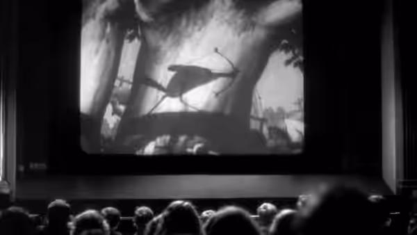 Cinema audiences watch a projected film showing a vehicle on a road