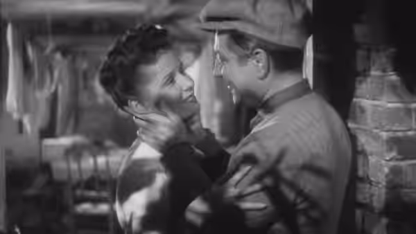 Françoise (Jacqueline Laurent) embraces François (Jean Gabin) inside a room