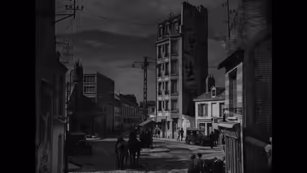Pedestrians cross a quiet street lined with tall apartment buildings