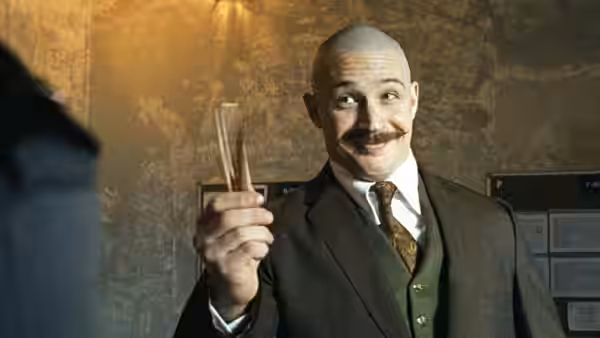 Charles Bronson (Tom Hardy) holds a narrow object while wearing a suit and waistcoat