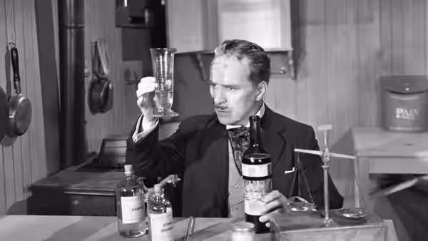 Henri Verdoux (Charlie Chaplin) examines a glass among bottles and laboratory equipment