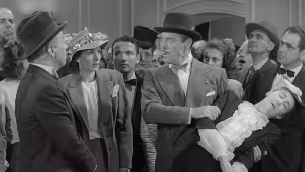 Henri Verdoux (Charlie Chaplin) carries an unconscious woman among formally dressed guests