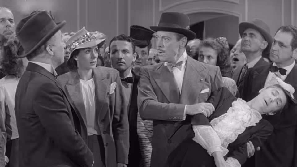 Henri Verdoux (Charlie Chaplin) carries an unconscious woman among formally dressed guests