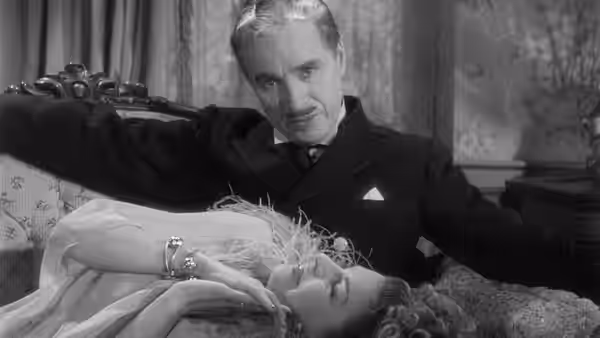 Henri Verdoux (Charlie Chaplin) leans over a woman lying on a bed