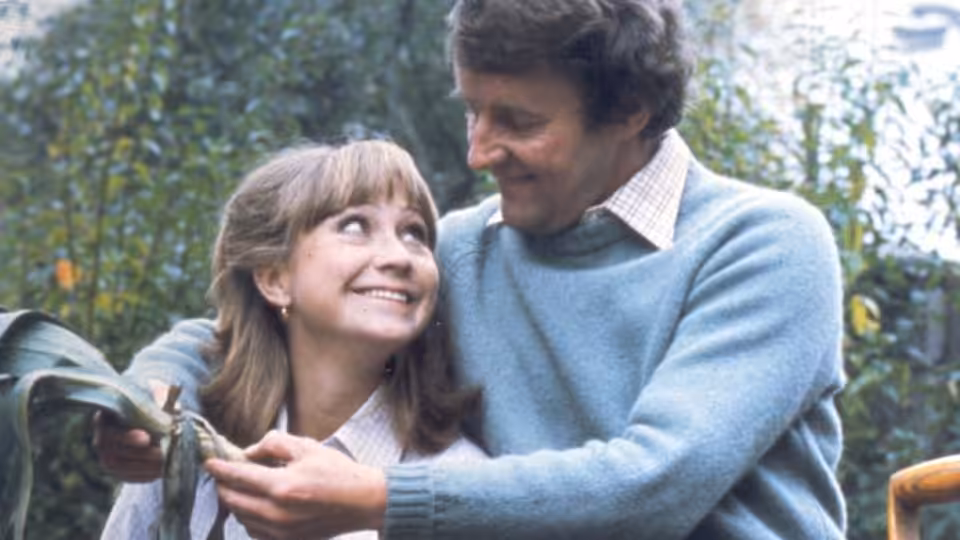 Barbara Good and Tom Good smiling while holding cut foliage outdoors
