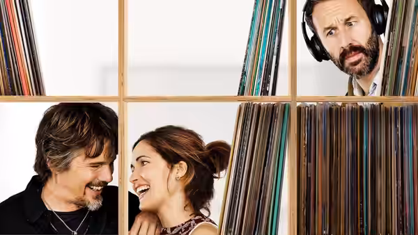 Tucker Crowe (Ethan Hawke) and Annie Platt (Rose Byrne) peer through record shelves with a man wearing headphones
