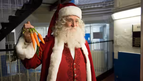 Santa Claus (Jim Broadbent) holds carrots inside a building