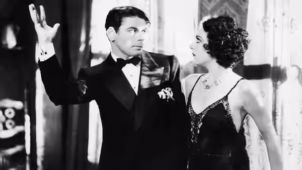Tony Camonte (Paul Muni) raises a hand beside Poppy (Karen Morley) at a nightclub